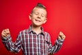 Young little caucasian kid with blue eyes standing wearing elegant shirt over red background very happy and excited doing winner Royalty Free Stock Photo