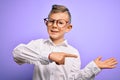 Young little caucasian kid with blue eyes wearing glasses and white shirt over purple background amazed and smiling to the camera Royalty Free Stock Photo