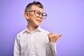 Young little caucasian kid with blue eyes wearing glasses and white shirt over purple background smiling with happy face looking Royalty Free Stock Photo