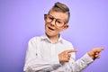 Young little caucasian kid with blue eyes wearing glasses and white shirt over purple background smiling and looking at the camera Royalty Free Stock Photo