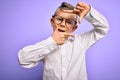 Young little caucasian kid with blue eyes wearing glasses and white shirt over purple background smiling making frame with hands Royalty Free Stock Photo