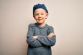 Young little caucasian kid with blue eyes wearing wool cap over isolated background happy face smiling with crossed arms looking Royalty Free Stock Photo