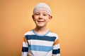 Young little caucasian kid injured wearing medical bandage on head over yellow background with a happy and cool smile on face