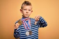 Young little caucasian winner kid wearing award competition medals over yellow background with angry face, negative sign showing
