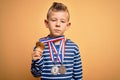 Young little caucasian winner kid wearing award competition medals over yellow background with a confident expression on smart