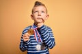 Young little caucasian winner kid wearing award competition medals over yellow background serious face thinking about question,