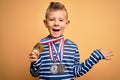 Young little caucasian winner kid wearing award competition medals over yellow background very happy and excited, winner
