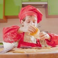 Young little chef girl with cook hat and apron preparing sweet desert at home kitchen. Nutrition and education concept Royalty Free Stock Photo