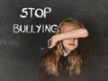 Young little cute schoolgirl scared sad covering her face and the words stop bullying text