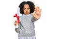 Young little girl with afro hair holding graduate degree diploma with open hand doing stop sign with serious and confident