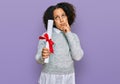 Young little girl with afro hair holding graduate degree diploma serious face thinking about question with hand on chin,