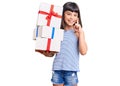 Young little girl with bang holding gifts surprised with an idea or question pointing finger with happy face, number one Royalty Free Stock Photo