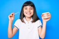 Young little girl with bang holding invisible aligner orthodontic and braces smiling with a happy and cool smile on face