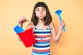 Young little girl with bang playing with summer shovel and bucket toys puffing cheeks with funny face