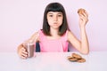 Young little girl with bang sitting on the table having breakfast puffing cheeks with funny face Royalty Free Stock Photo