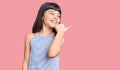 Young little girl with bang wearing casual clothes smiling with happy face looking and pointing to the side with thumb up Royalty Free Stock Photo