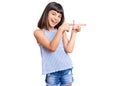 Young little girl with bang wearing casual clothes smiling and looking at the camera pointing with two hands and fingers to the Royalty Free Stock Photo