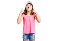 Young little girl with bang wearing funny kitty cap amazed and surprised looking up and pointing with fingers and raised arms Royalty Free Stock Photo