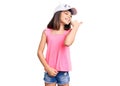 Young little girl with bang wearing funny kitty cap smiling with happy face looking and pointing to the side with thumb up Royalty Free Stock Photo