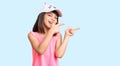 Young little girl with bang wearing funny kitty cap smiling and looking at the camera pointing with two hands and fingers to the Royalty Free Stock Photo