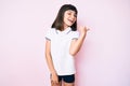 Young little girl with bang wearing sportswear smiling with happy face looking and pointing to the side with thumb up Royalty Free Stock Photo