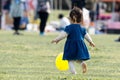 A young little girl chasing a yellow balloon and play with it in the park.