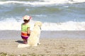 Young Little Girl And Golden Retriever Dog Sitting On The Beach.Girl Sitting Alone With Her Dog. Royalty Free Stock Photo
