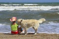 Young Little Girl And Golden Retriever Dog Sitting On The Beach.Girl Sitting Alone With Her Dog. Royalty Free Stock Photo