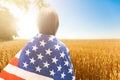 Young little girl holding American flag on amazing sky, mountain and meadow nature background at sunset. Royalty Free Stock Photo