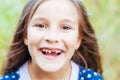 Young little girl with long hair without front tooth smiles, natural light