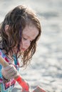 Young little girl playing with the sand and building sandcastle at the beach near the sea. Royalty Free Stock Photo