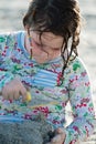 Young little girl playing with the sand and building sandcastle at the beach near the sea. Royalty Free Stock Photo