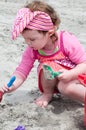 Young little girl playing with the sand and building sandcastle at the beach near the sea. Royalty Free Stock Photo