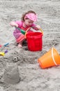 Young little girl playing with the sand and building sandcastle at the beach near the sea. Royalty Free Stock Photo