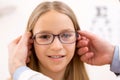 Young little girl trying glasses at the optician