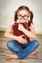 Young little girl wearing glasses sitting on the floor and holding books