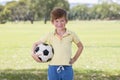 Young little kid 7 or 8 years old enjoying happy playing football soccer at grass city park field posing smiling proud standing ho Royalty Free Stock Photo