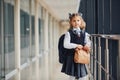 Young little school girl in uniform standing in hallway with package of dinner in hands Royalty Free Stock Photo