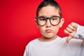 Young little smart boy kid wearing nerd glasses over red isolated background with angry face, negative sign showing dislike with Royalty Free Stock Photo