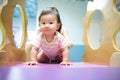 Young little smiling Asian baby enjoy playing in kid playground. Mother holding baby from her back to play on slider with Royalty Free Stock Photo