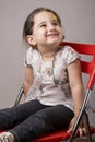 Young little two years old girl seat on a red chair in front of Royalty Free Stock Photo