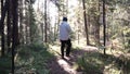 Young lonely man walking deep into forest among dense vegetation and bushes. Footage. View of man from back walking on Royalty Free Stock Photo