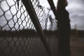 young lonely teenage girl looks at the iron mesh fence into the distance and renounced alone with herself thinks and is Royalty Free Stock Photo