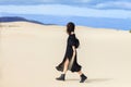 Young lonely woman in long black dress walking in desert holding Royalty Free Stock Photo