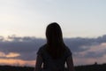 Young lonely woman looks at the sunset.