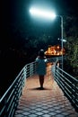 Young lonely woman walking on the bridge at night