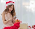 A young long brown hair female wearing red and white christmas hat and pink sleeveless dress using her silver mobile phone Royalty Free Stock Photo