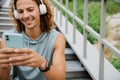 Young long-haired athletic smiling man in headphones using phone Royalty Free Stock Photo