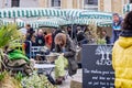 Young long haired and bearded man sat reading book at outdoor cafe at Frome Sunday Market, Somerset, UK