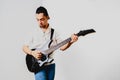 Young long haired guitarist excited playing his black electric guitar, isolated on white background